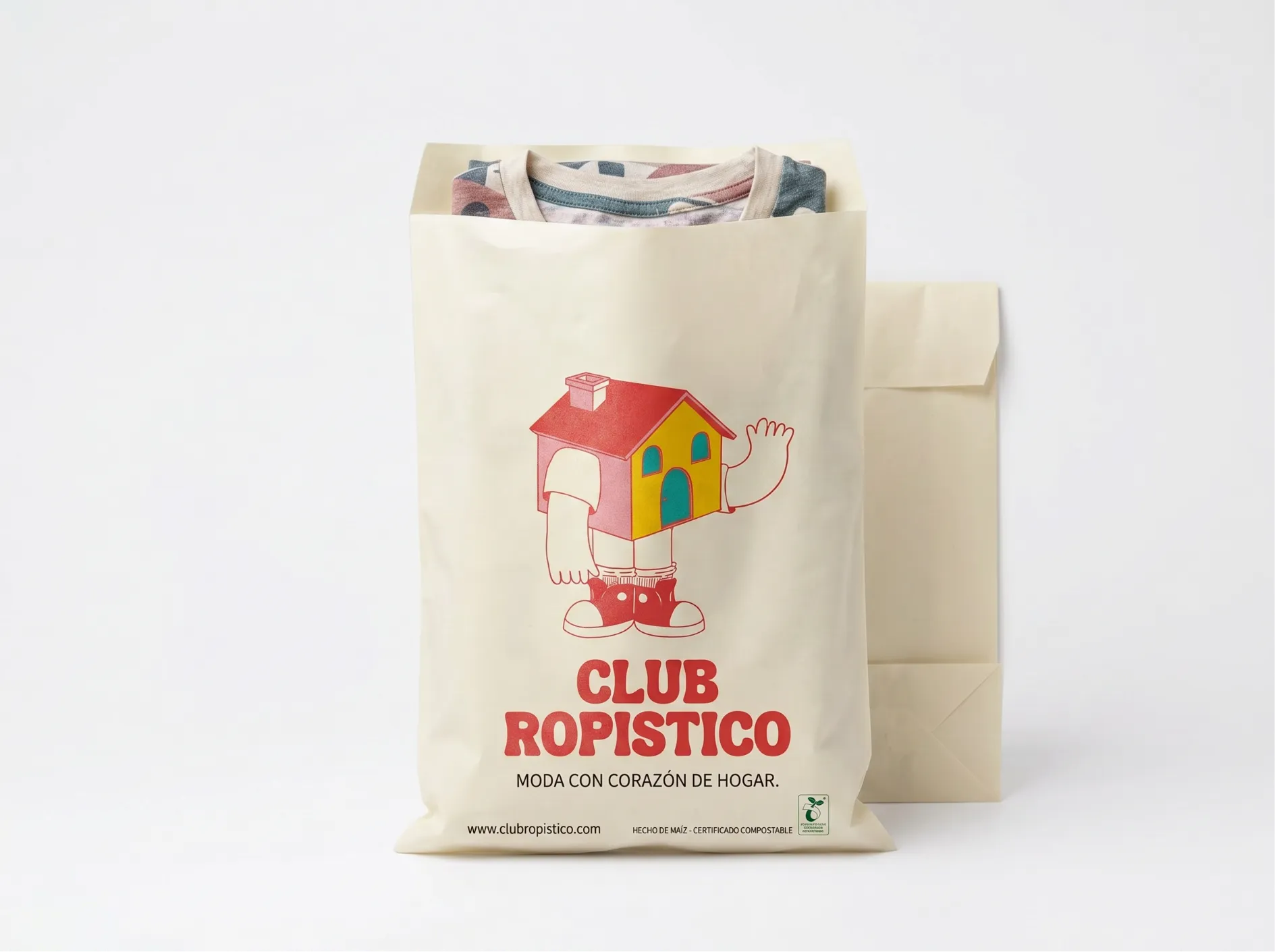 Cream Club Ropístico garment packaging with the house mascot, red wordmark and a folded tee inside.